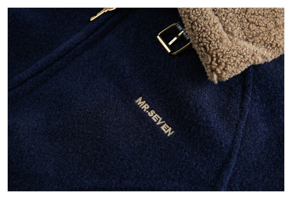 Close-up of navy jacket fabric, tan collar trim, a brass buckle, and a small embroidered wordmark.