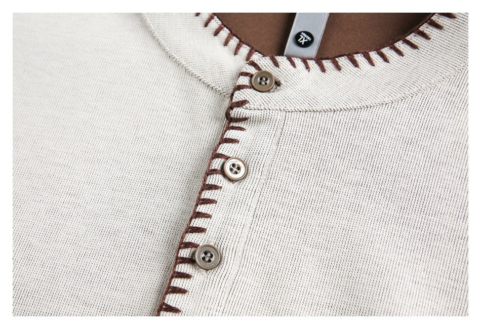 Close-up of a cream shirt's front neckline and button placket with brown blanket stitching and three buttons.