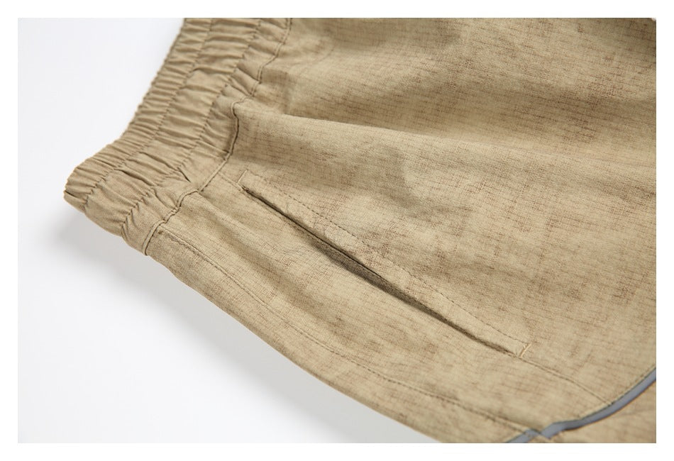 Close-up of the tan pants' elastic waistband and angled side pocket.