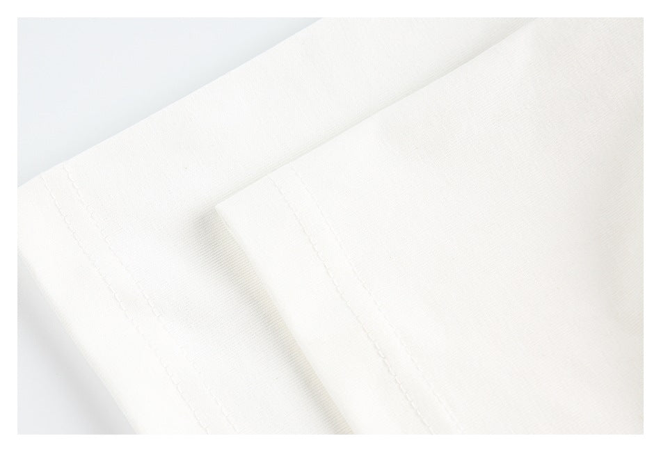 Close-up of a white garment with a double-stitched edge and fine texture.