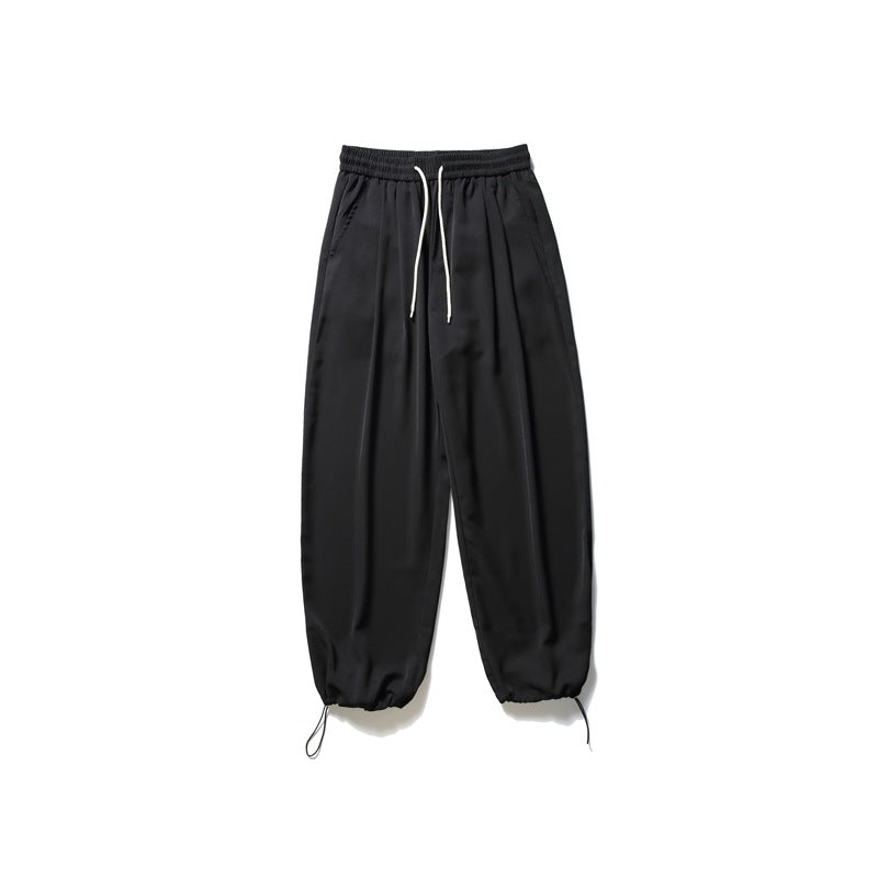 Black wide-leg pants with elastic drawstring waist, side pockets and gathered drawstring ankle hems, flat lay