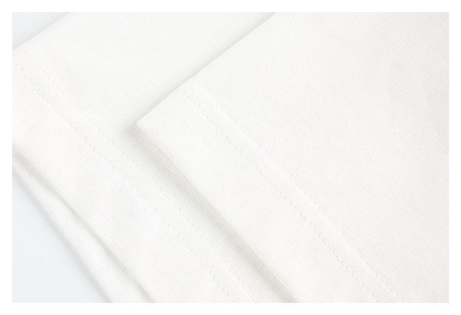 Close-up of white garment fabric with overlapping folded sections and stitched seams.