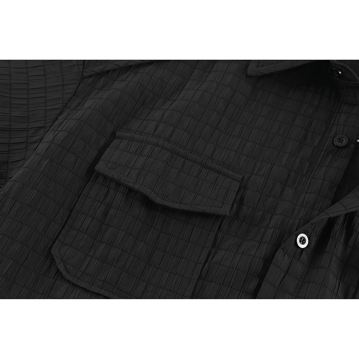 Close-up of a black shirt’s buttoned flap chest pocket and textured fabric.