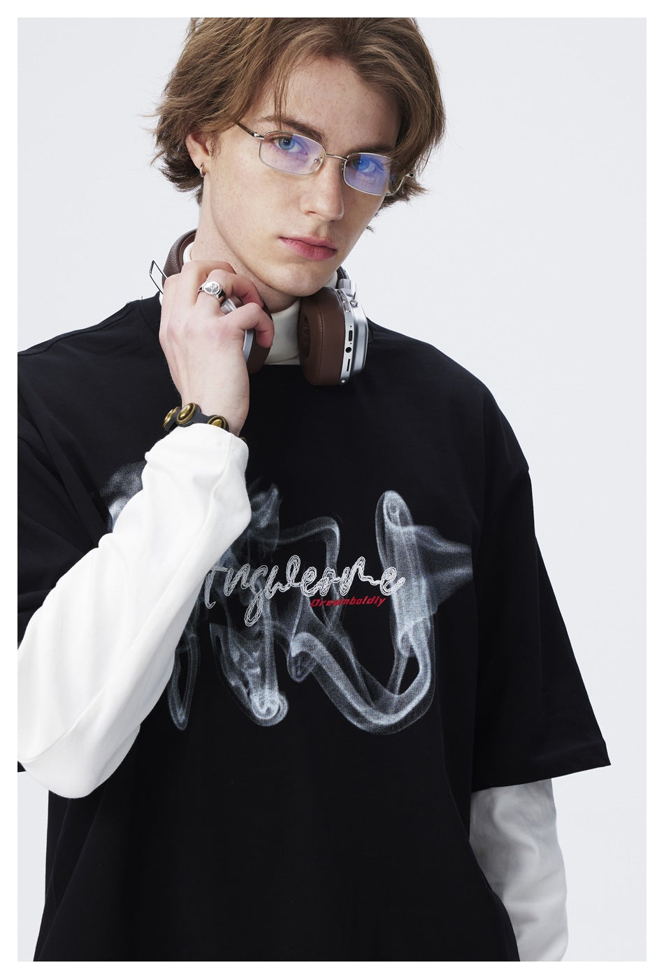 Close-up of a black T-shirt's large smoky graphic and lettering, worn over a white sleeve.