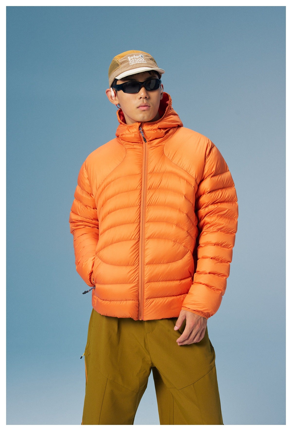 Closer front view of a model in an orange hooded puffer jacket with curved quilted panels.