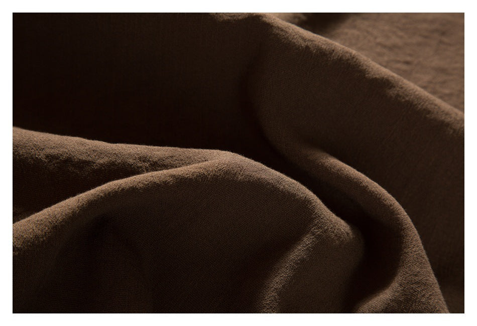 Close-up of softly folded brown garment fabric in shadow.