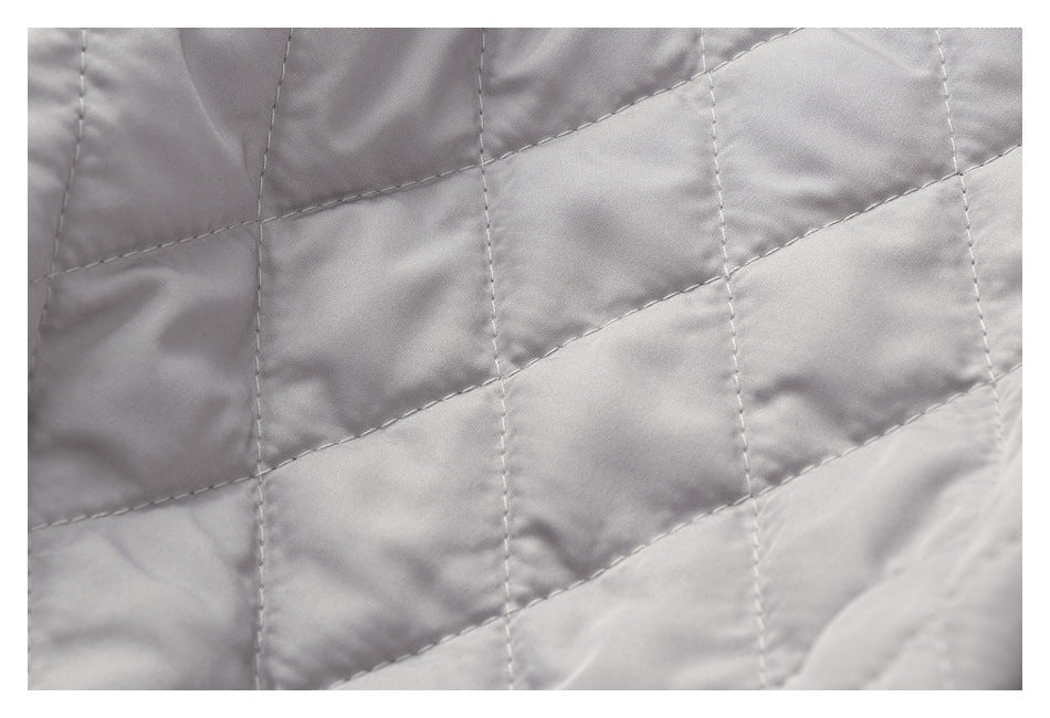 Close-up of light gray quilted fabric with intersecting stitched lines forming large sections.