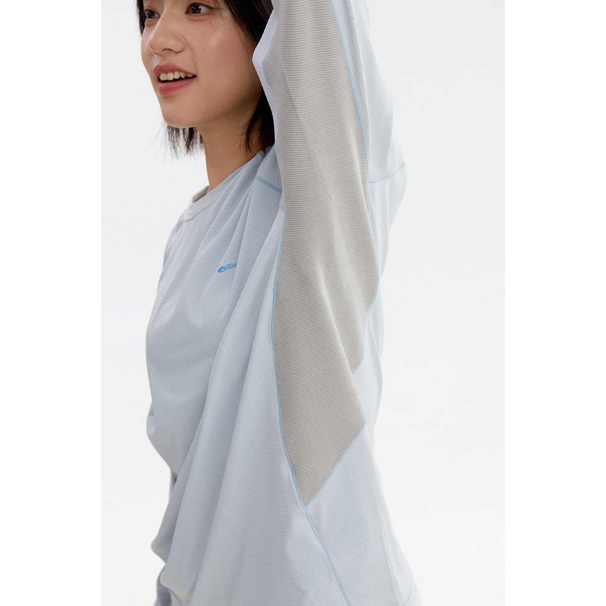 Close-up of a pale blue long-sleeve top showing its contrasting gray sleeve panel, seams, and small chest mark.