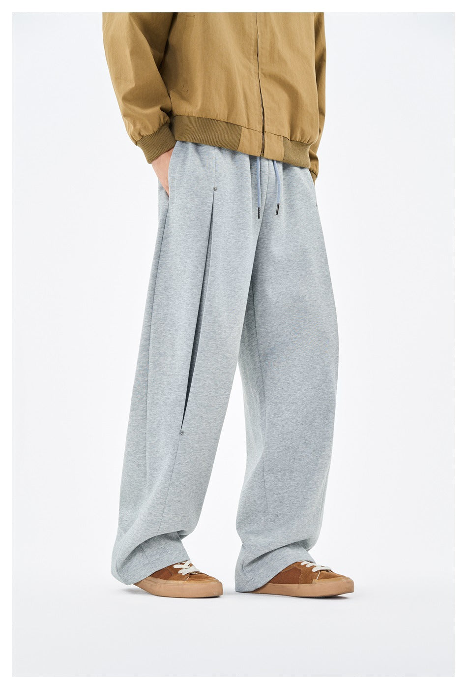 Person wearing heather gray wide-leg sweatpants with a tan zip jacket and brown sneakers, three-quarter view