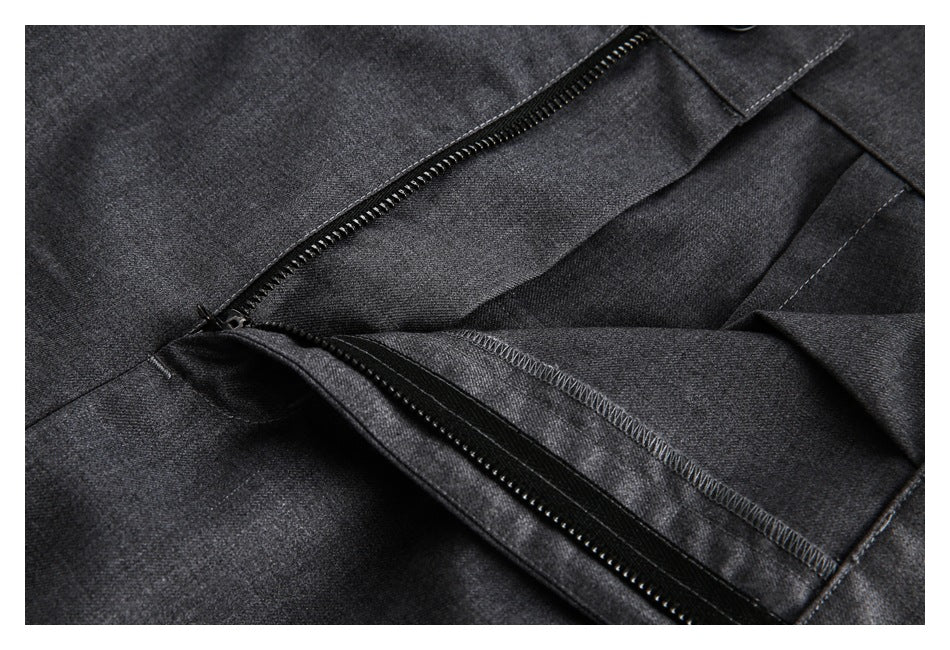 Close-up of charcoal gray trousers showing the open front zipper and inner seam finishing.
