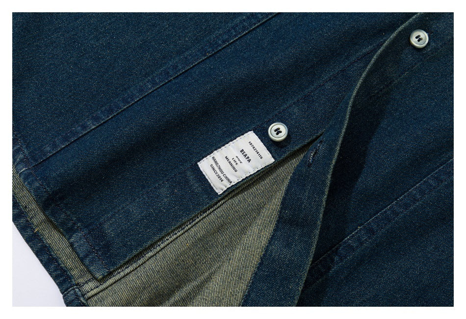 Close-up of a dark blue denim garment opening, showing two buttons, a stitched label, and the inside fabric.