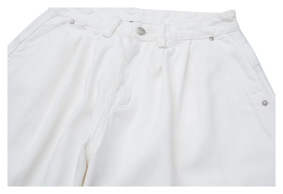 Close-up front view of white jeans showing the button, waistband, belt loops, and front pockets.