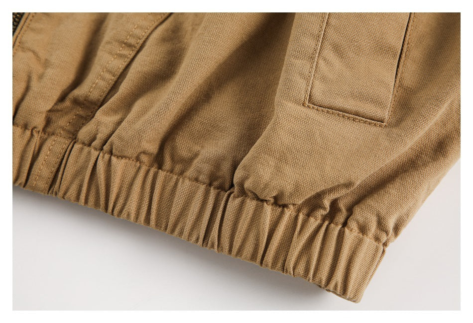 Close-up of the tan jacket's elasticated hem and rectangular welt pocket.