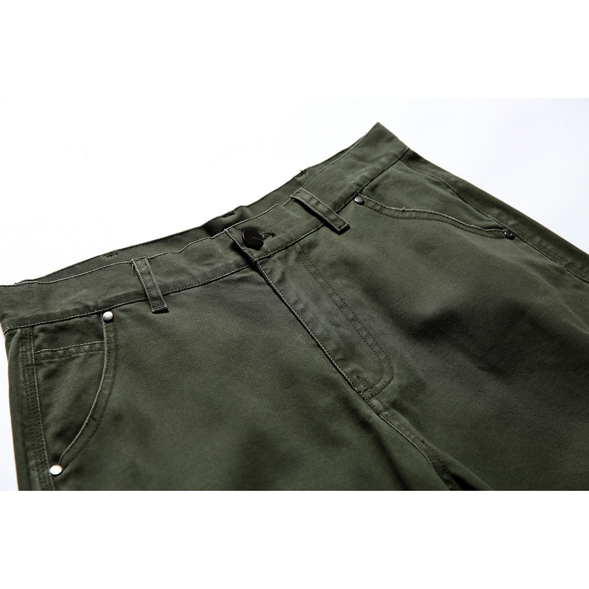 Close-up of olive shorts showing the button waistband, belt loops, fly, and riveted front pocket.