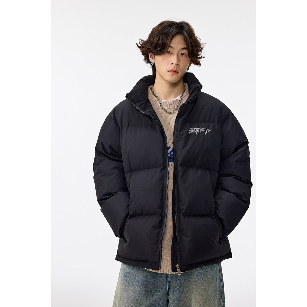 Man wearing a black quilted puffer jacket with a high collar and front zipper.