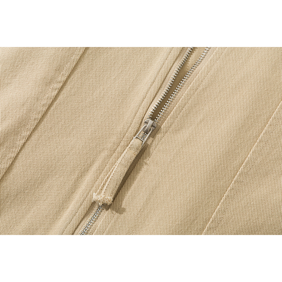 Close-up of a metal zipper and stitching on beige twill fabric.