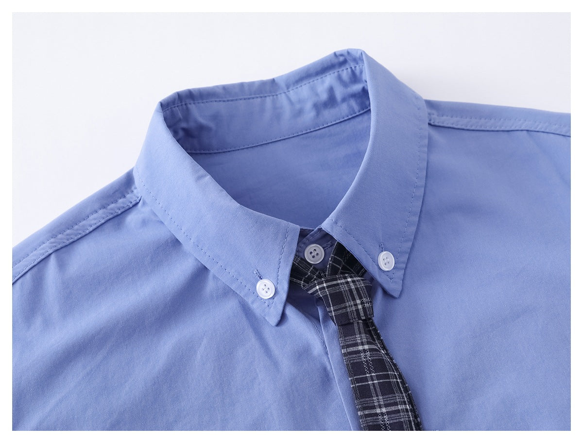 Close-up of a light blue button-down shirt collar with white buttons and a black plaid tie.