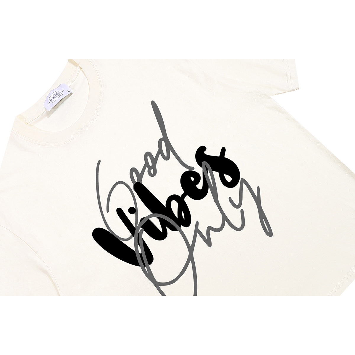 Close-up of an ivory T-shirt with a large black and gray script graphic on the front.