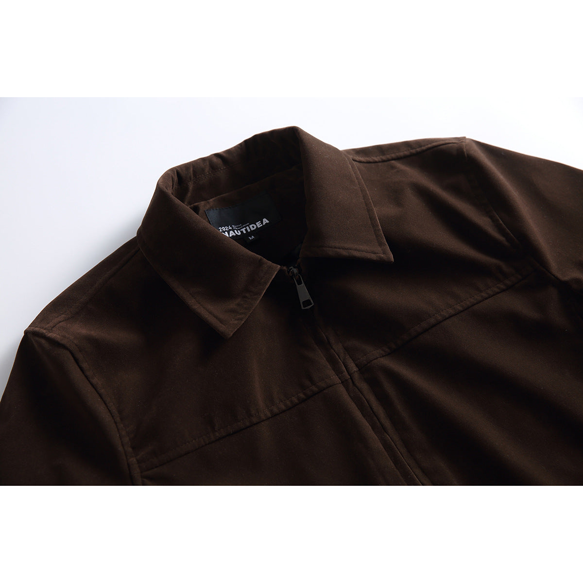 Close-up of a dark brown jacket collar, zipper, chest seams, and sewn-in neck label.