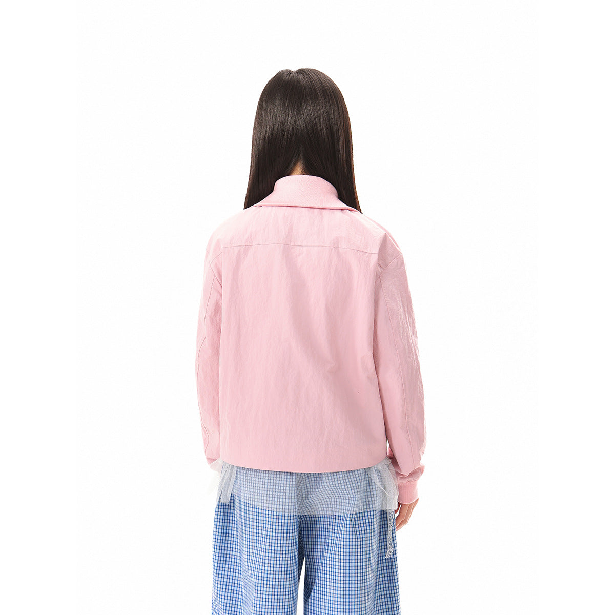 Back view of a model wearing a light pink collared jacket with long sleeves and blue checkered trousers.
