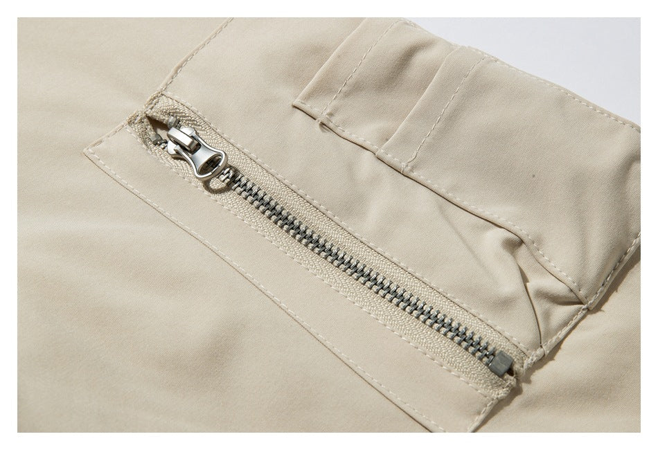 Close-up of a silver zipper and stitched placket on a light beige garment.