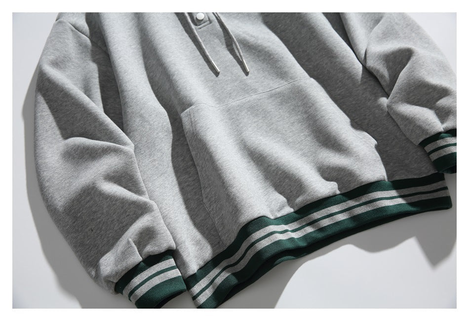 Close-up of the gray hoodie’s kangaroo pocket and green-and-gray striped cuffs and hem.