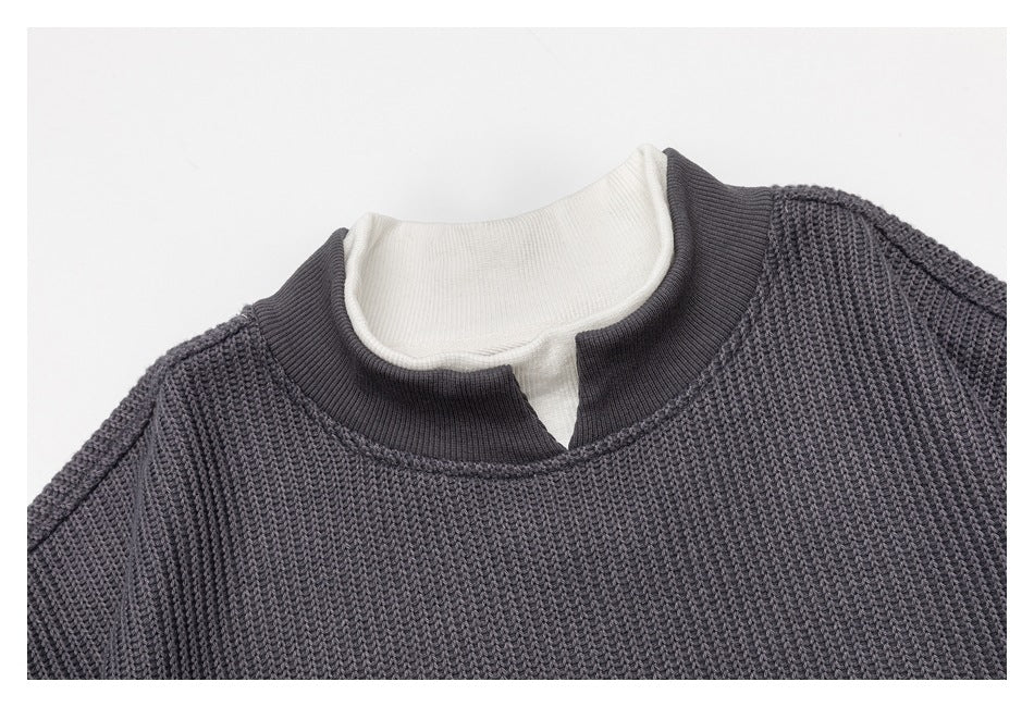 Close-up of the charcoal pullover's textured knit and split stand collar, layered over a white shirt.