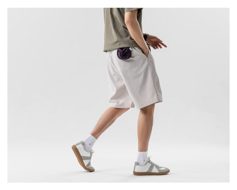 Side and rear view of a model wearing light gray shorts with a small purple pouch attached at the back pocket.
