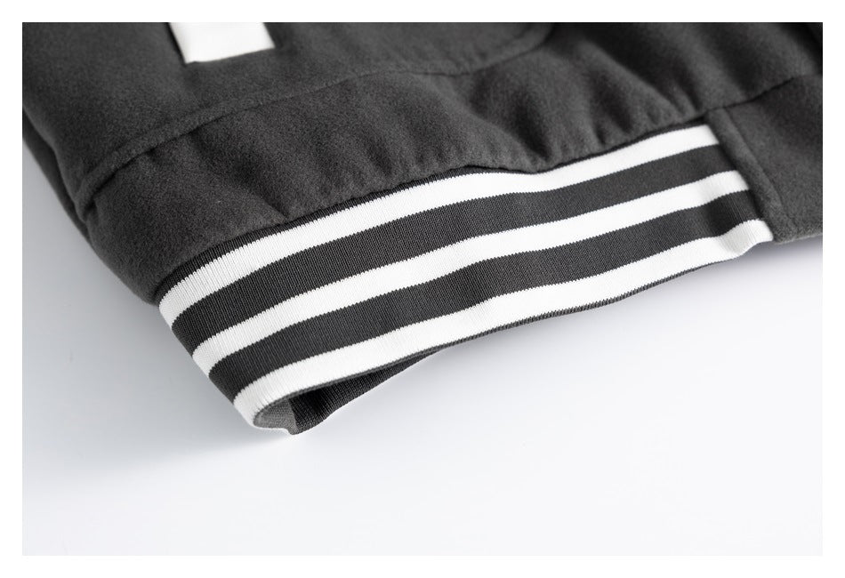 Close-up of a dark jacket sleeve ending in a black-and-white striped ribbed cuff.