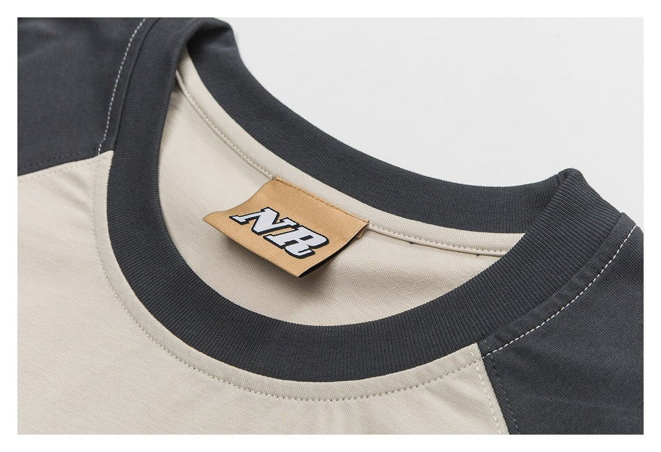 Close-up of a beige and charcoal crew-neck shirt collar with a small tan neck label.