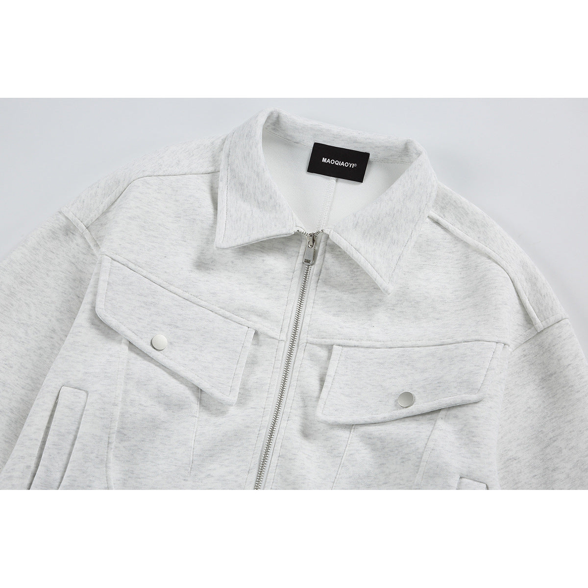 Close-up of a light gray zip-front jacket with a pointed collar and snap-button chest flap pockets.