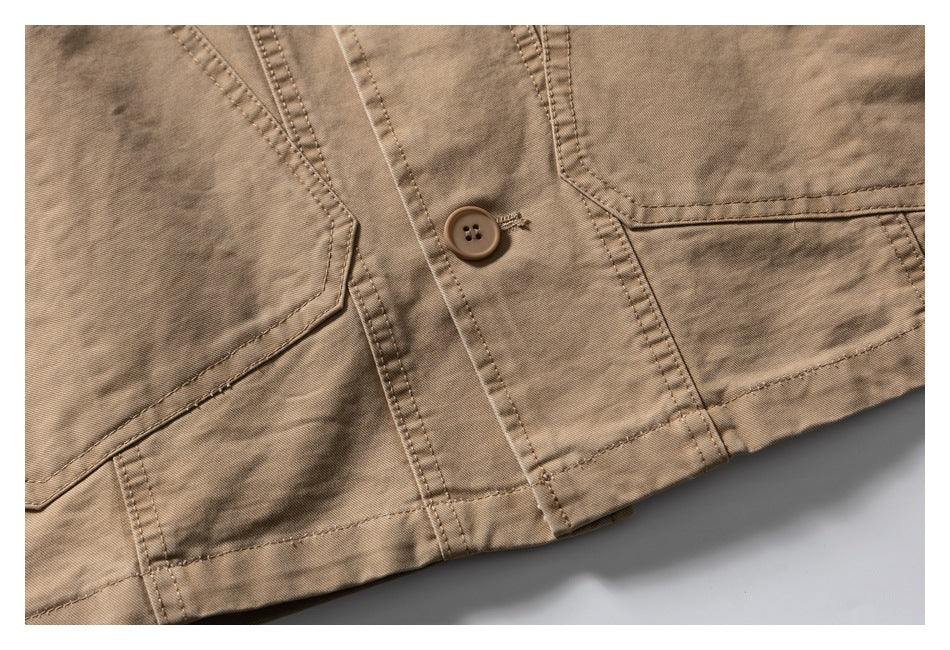 Close-up of the tan jacket front with a button, stitched seams, and angular pocket edges.