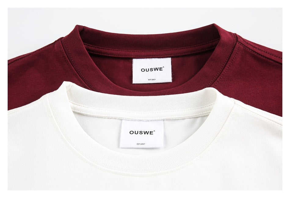 Close-up of cream and burgundy T-shirt crew necks with white OUSWE neck labels.
