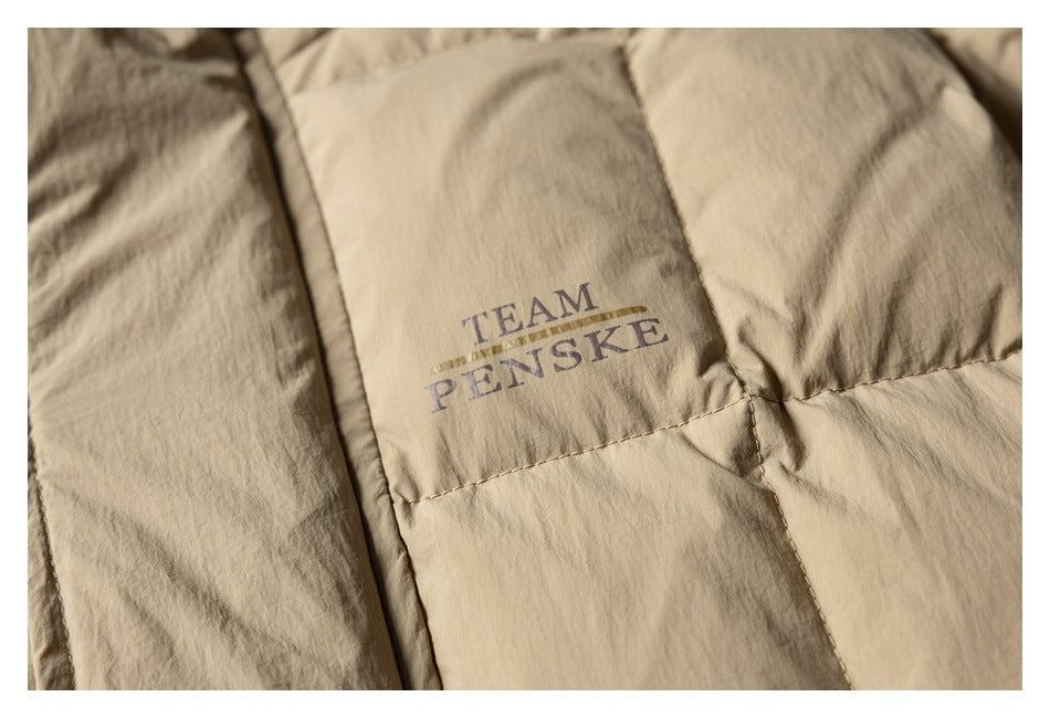Close-up of a tan quilted jacket with “TEAM PENSKE” printed on a panel.