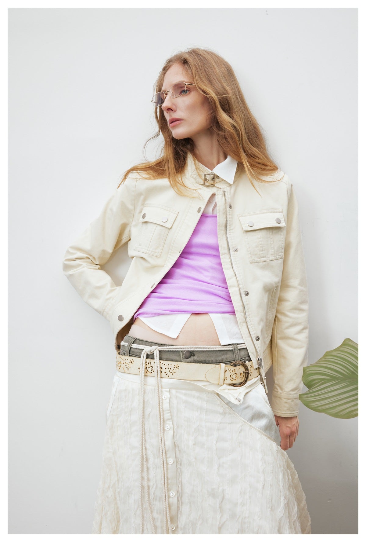 Model wearing an ivory cropped utility jacket with flap chest pockets, layered over a lilac top.