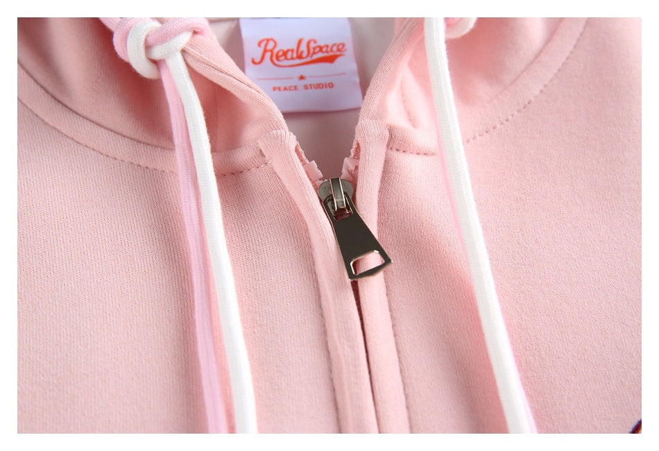 Close-up of the pale pink hoodie’s zipper, white drawstrings and sewn-in neck label.