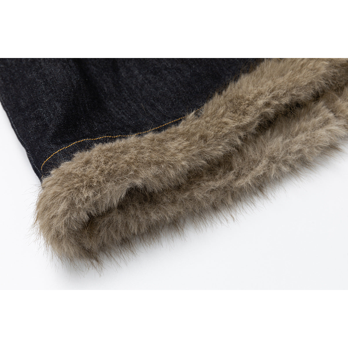 Close-up of a taupe faux-fur trim along the edge of dark denim with ochre stitching.