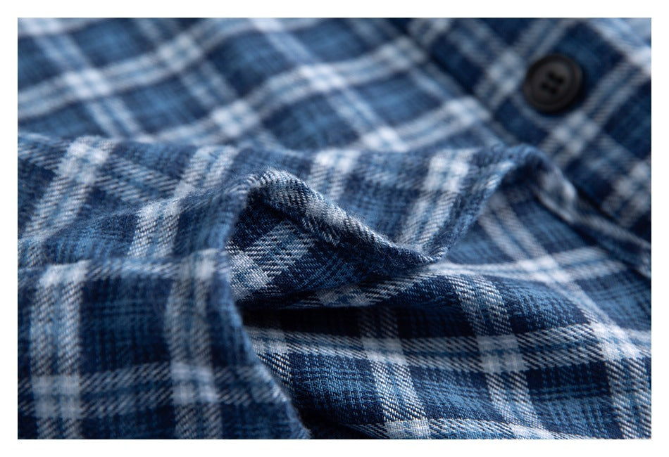 Close-up of the blue-and-white plaid shirt fabric, showing its weave and a black button.