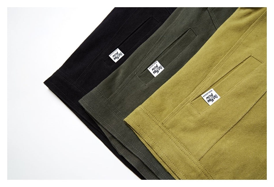 Three jackets in black, dark olive, and mustard, showing rear pocket details and small sewn labels.