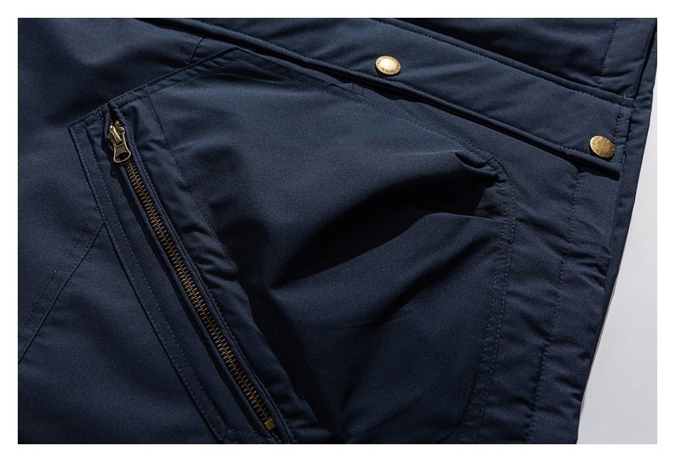 Close-up of a navy jacket pocket with a brass-colored zipper and matching snap buttons.