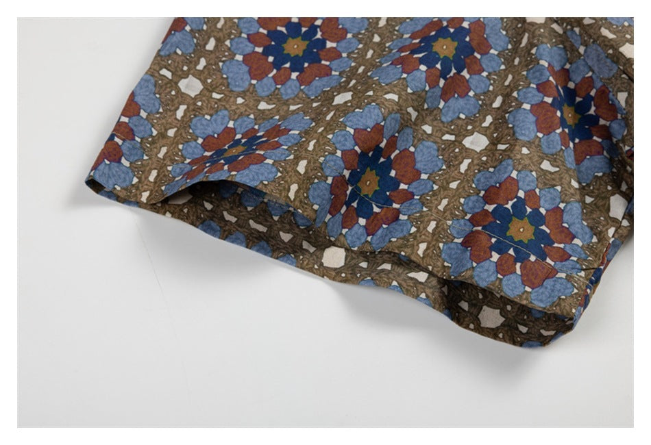 Close-up of a sleeve edge on a brown shirt with blue and rust floral geometric print.