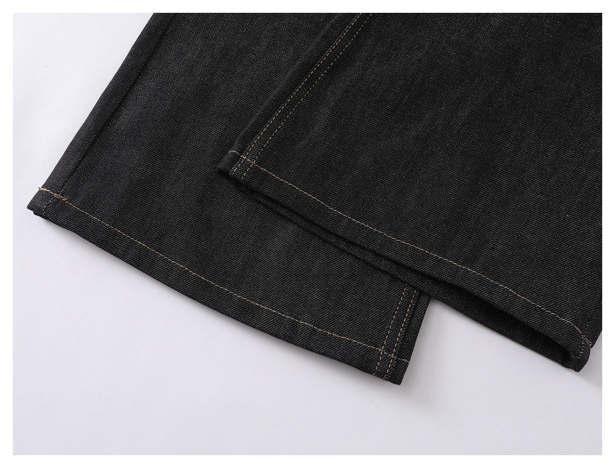 Close-up of the hem and stitched seam on black denim jeans laid flat.