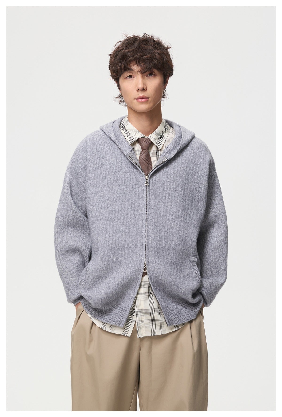 Front view of a model wearing a light gray hooded knit jacket with a two-way zipper and front pockets.