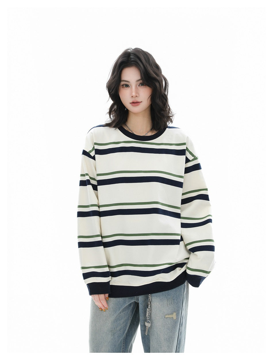 Model wearing an ivory oversized shirt with navy and green stripes, dark ribbed trim, and light-wash jeans.