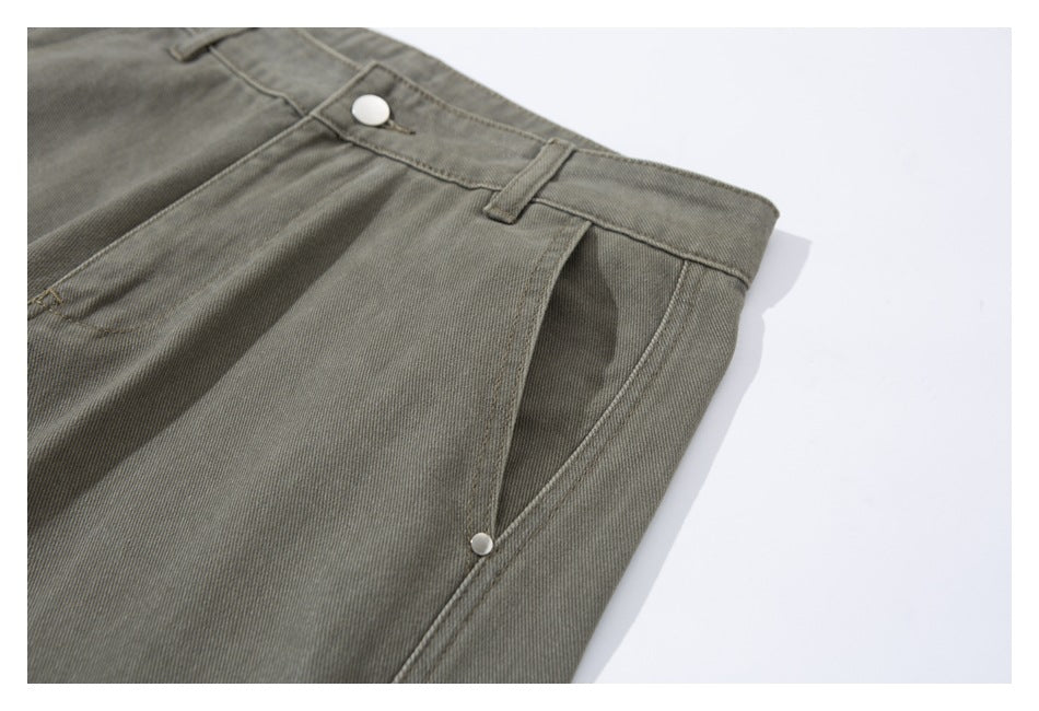 Close-up of olive-gray pants showing the front waistband, white button, belt loop, and pocket opening.