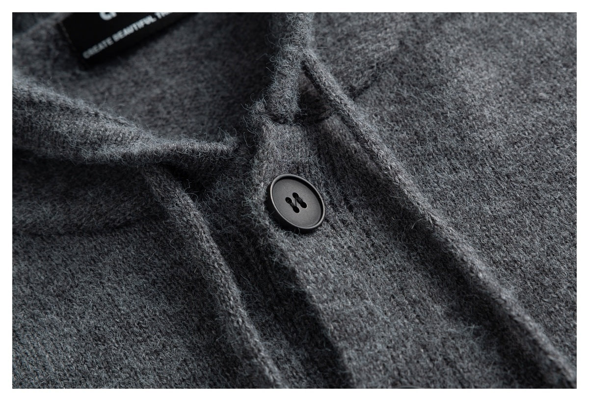 Close-up of a dark gray fuzzy knit garment with a black button and overlapping fabric edges.