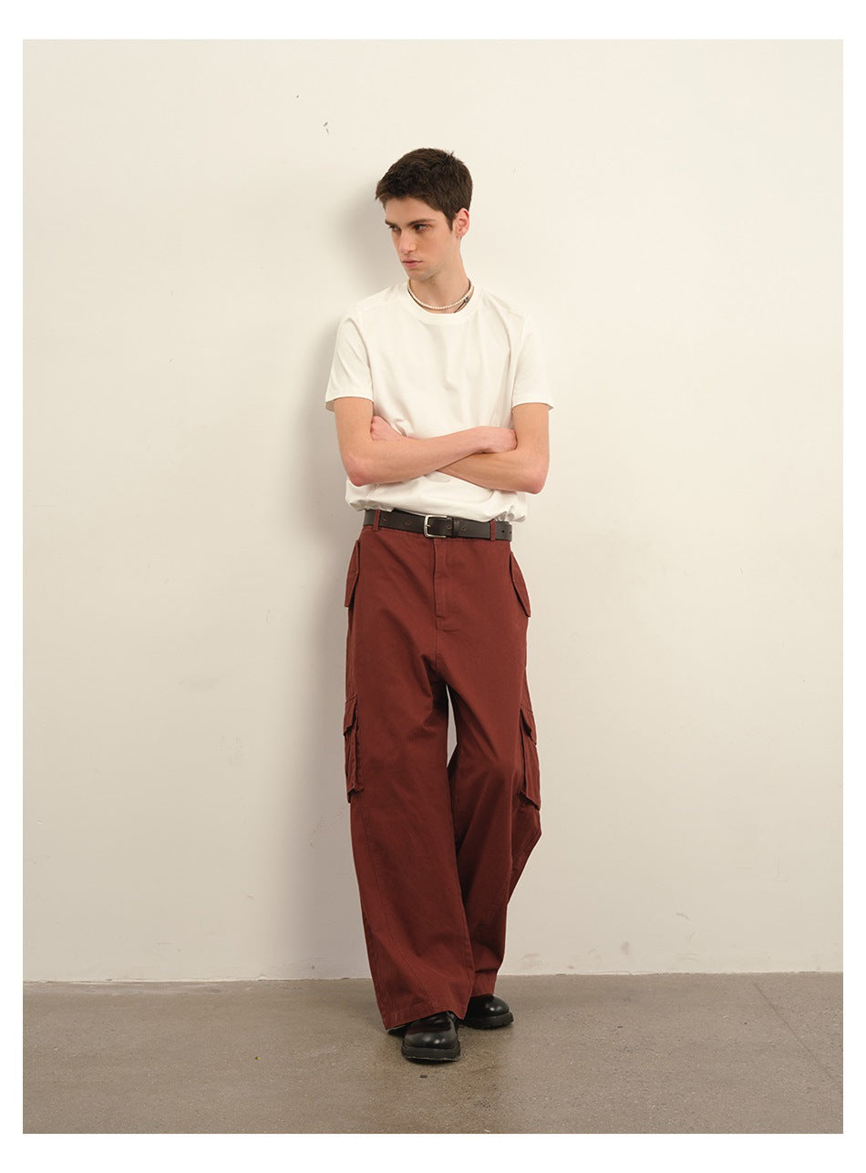 Model wearing rust-red wide-leg cargo trousers with a white T-shirt and black belt.