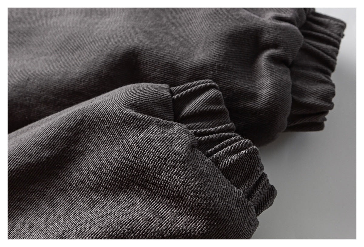 Close-up of gathered elastic cuffs on folded charcoal garment fabric.