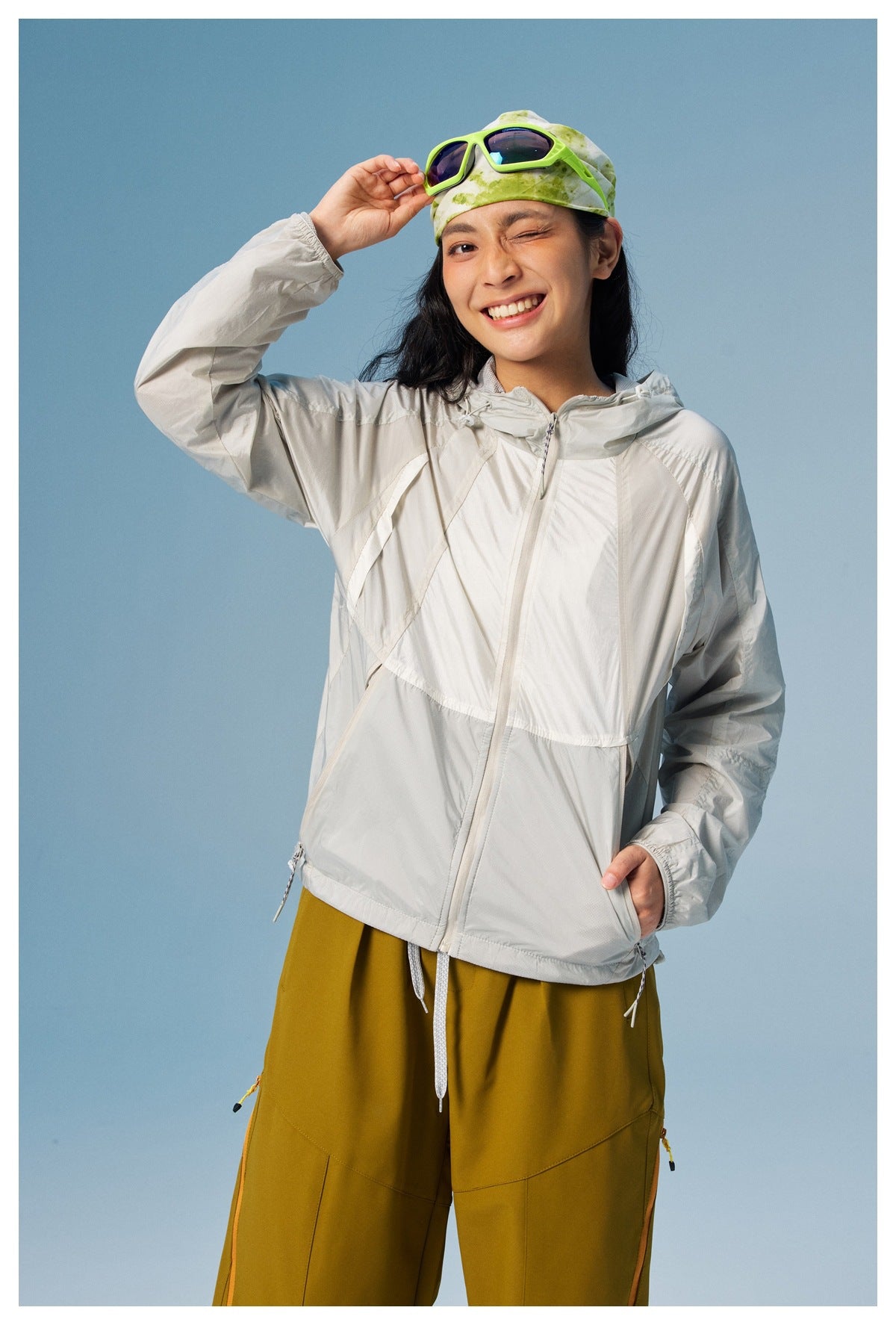 Model wearing a light gray color-block hooded jacket with mustard yellow pants.