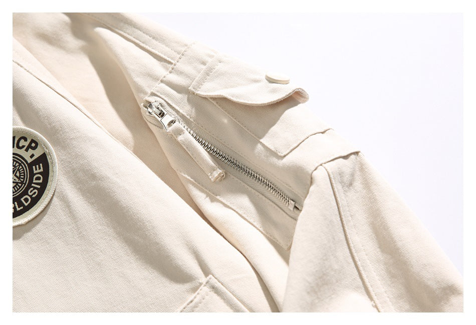 Close-up of an ivory jacket sleeve with a zippered pocket and a snap-fastened flap.